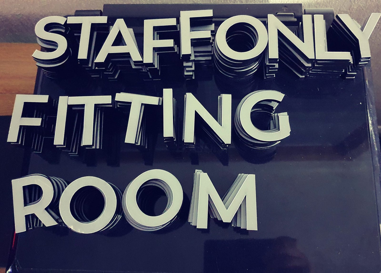Stacks of laser cut acrylic letters spelling Staff Only Fitting Room before installation